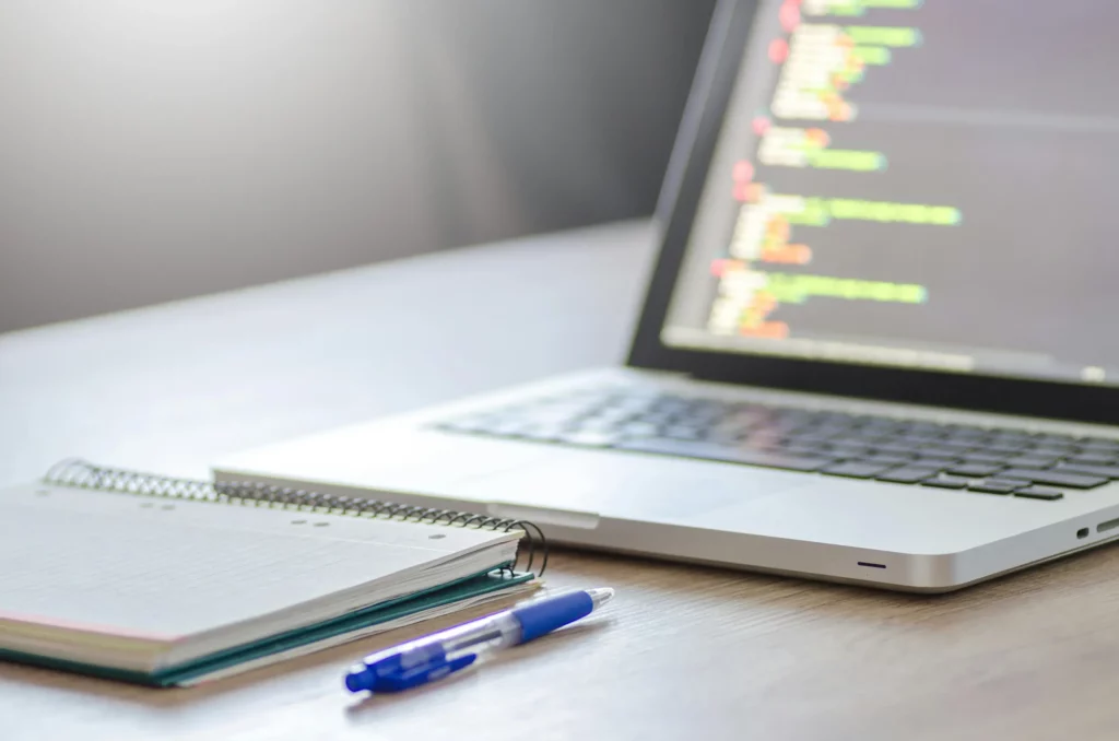 Laptopt with notebook and pen, it represent Mellonne's automated compliance testing expertise